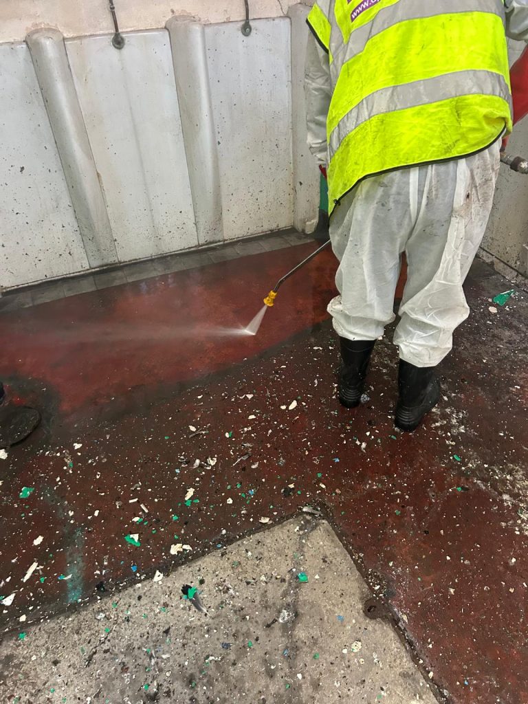 JWL operative in hi-vis jet washing a commercial bin store