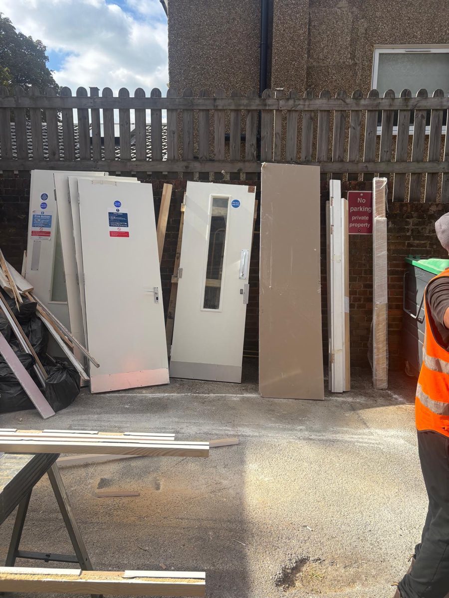 Office doors and panels from a strip-out stacked in a rear yard